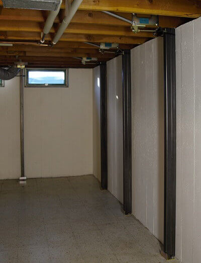 a basement with white walls and Gorilla Wall Braces installed to straighten the bowing basement walls.